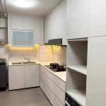 L-shaped modern white kitchen cabinet with integrated tall oven housing unit and gas cooktop